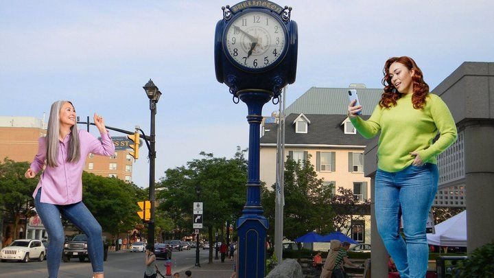 A grey-haired woman mid-dance and a smiling red-haired woman checking her phone, with Burlington in the background